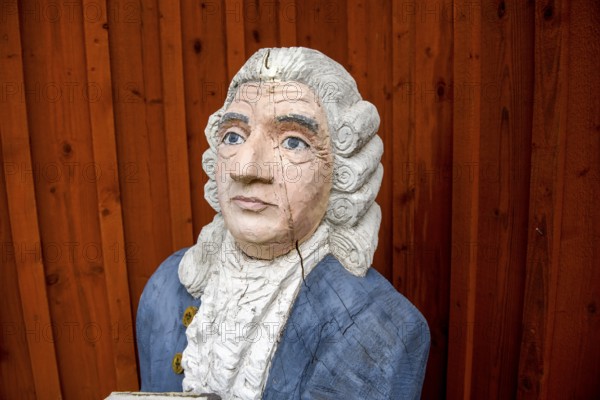 Wooden statue of botanist and founder of the binary nomenclature Carl von Linné with white hair and blue jacket in front of a wooden wall, Linnés Råshult, Älmhult, Kronobergs län, Småland, Sweden