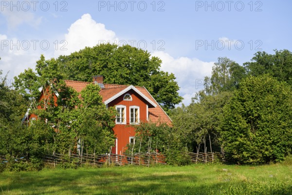 Charming red house with white windows, surrounded by trees and a wooden fence at the birthplace of botanist and founder of the binary nomenclature Carl von Linné, Linnés Råshult, Älmhult, Kronobergs län, Småland, Sweden