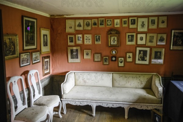 Historic living room with lots of framed pictures on the wall. An antique sofa and chairs stand on the wooden floor in the birthplace of botanist and founder of the binary nomenclature Carl von Linné, Linnés Råshult, Älmhult, Kronobergs län, Småland, Sweden