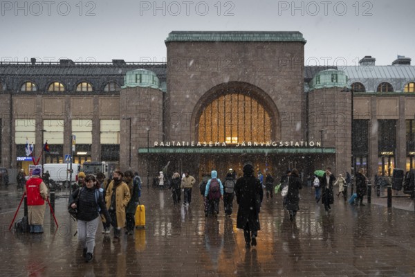 Busy side entrance to Central Station with Christmas decoration during snowfall, Helsinki, Finland