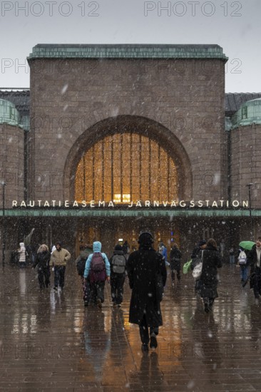 Busy side entrance to Central Station with Christmas decoration during snowfall, Helsinki, Finland