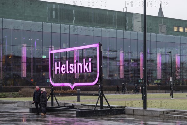 Tourists in front of Helsinki's big pink city logo, near Oodi Central Library and Cultural Center, Helsinki, Finland