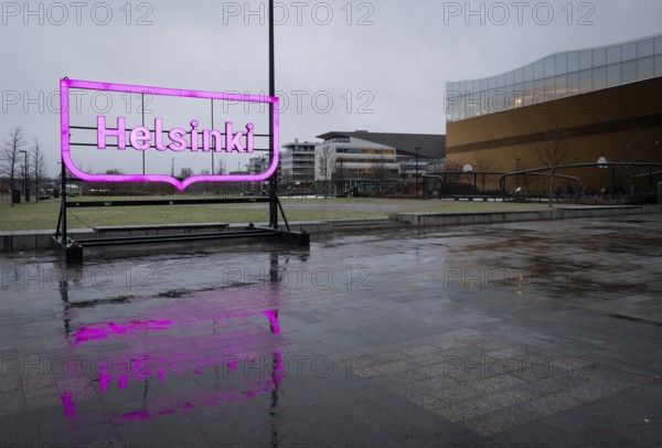 Large pink glowing Helsinki city logo, in front of Oodi Central Library and Cultural Center, designed by ALA Architects, Helsinki, Finland