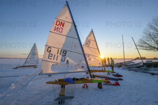 Ice sailboats in evening light and bright sun on the shore of a frozen lake Dümmer, Dümmer See, east shore north of Lembruch, Lembruch, Diepholz district, Lower Saxony, Germany