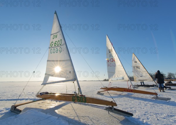 Three ice sailboats on frozen lake under clear blue sky and bright sunshine on frozen Dümmer, Dümmer See, east shore north of Lembruch, Lembruch, Diepholz district, Lower Saxony, Germany