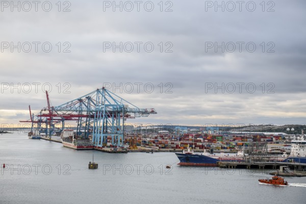 Industrial port with large cranes, container bridges and container ships under a cloudy sky, Gothenburg, Västra Götalands län, Sweden