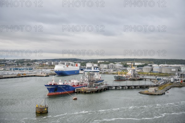 Industrial port with tanks and ships on calm water under a grey sky, Gothenburg, Västra Götalands län, Sweden