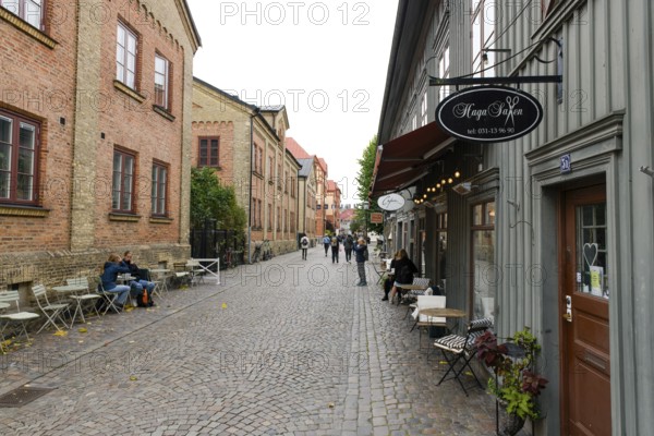 Lively street scene with cafés and historic buildings along a cobblestone street in Gothenburg's Haga district, Gothenburg, Västra Götalands län, Sweden
