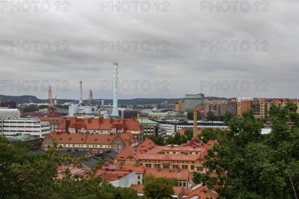 View of an urban landscape from Skansen with industrial elements and red roofs under a cloudy sky, Gothenburg, Västra Götalands län, Sweden