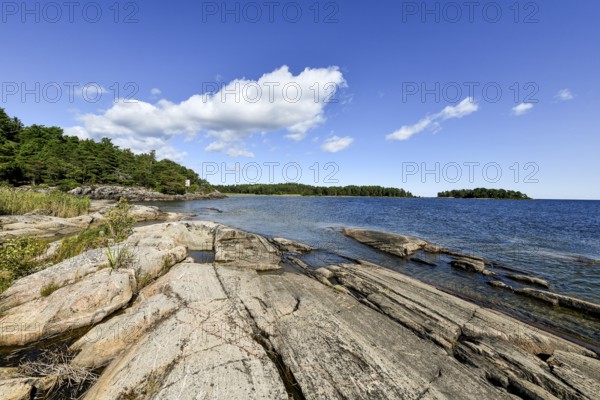 Clear sky over rocky archipelago coastline with granite archipelago with green forest and blue water at Lake Vänern, Värmlandsnäs peninsula, Värmlands län, Sweden