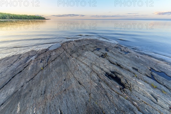 Far-reaching view of the quiet lake Vänern with gently sloping granite rocks archipelago under calm sky in the evening, Värmlands län, Sweden