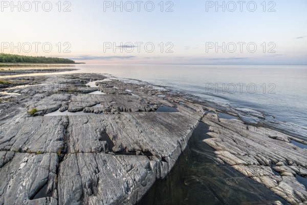 Far-reaching view of the quiet lake Vänern with gently sloping granite rocks archipelago under calm clear sky in the evening, Värmlands län, Sweden