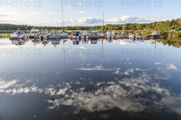 Several boats are moored in the quiet sports boat harbor of Ekenäs, water reflects the sky and the pleasure boats, Ekenäs, Värmlandsnäs peninsula, Värmlands län, Sweden