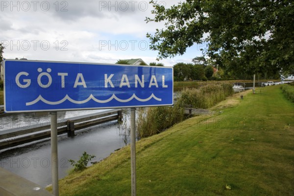 A sign for Göta Canal flanked by a road and green trees, Sjötorp, Västra Götalands län, Sweden