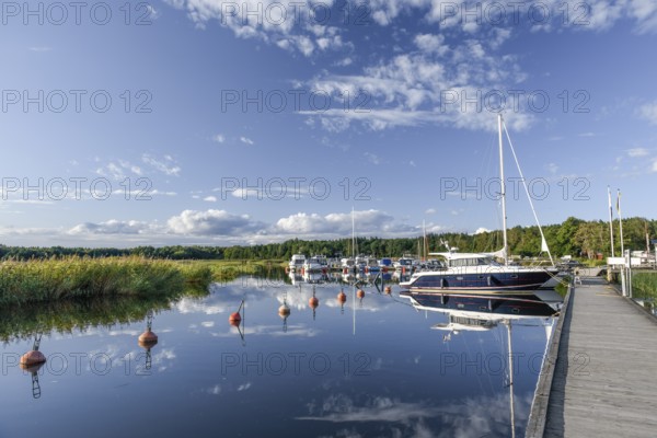 Several boats and a larger sailing yacht are moored in the quiet sports boat harbour of Ekenäs, water reflects the sky, Ekenäs, Värmlandsnäs peninsula, Värmlands län, Sweden