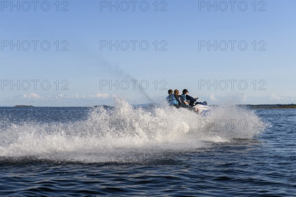 People ride fast across Lake Vänern on a jet ski and generate waves, Värmlandsnäs peninsula, Värmlands län, Sweden