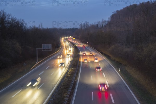 Night view of a motorway with fast moving cars and lights, surrounded by forest, near Stuttgart, Baden-Württemberg, Germany