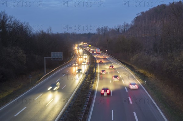 Cars move at night on an illuminated highway, surrounded by trees and darkness, near Stuttgart, Baden-Württemberg Germany