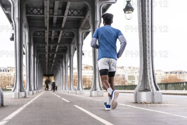 Young black man running on the bir hakeim bridge in paris, exercising in the modern urban environment of the city, focusing on health, wellness, and an active lifestyle