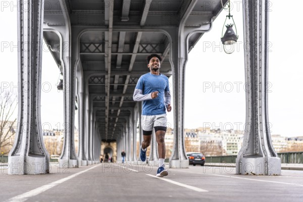 Young man smiling and running along the bir hakeim bridge in paris, engaging in urban sport and enjoying a healthy lifestyle during his morning exercise routine