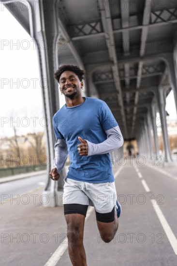 Smiling black man jogging on pariss bir hakeim bridge, staying fit and active in casual sportswear while enjoying urban training, energy and a healthy lifestyle outdoors
