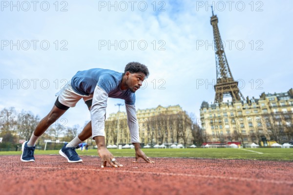 Young male athlete getting ready to run on an outdoor track in the heart of paris, focusing on the starting line with the eiffel tower prominent in the urban background