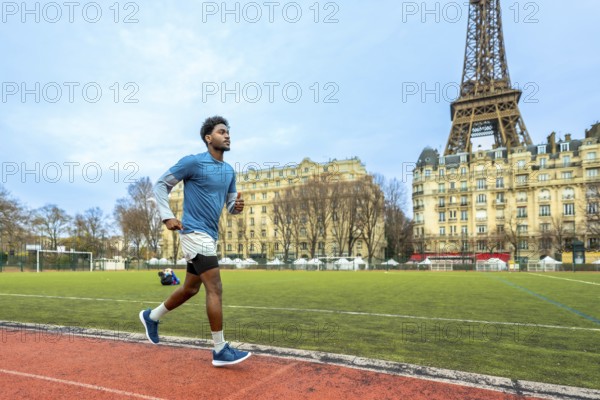 Young man training on a running track with the iconic eiffel tower and parisian buildings in the background, symbolizing urban fitness and sporty lifestyle