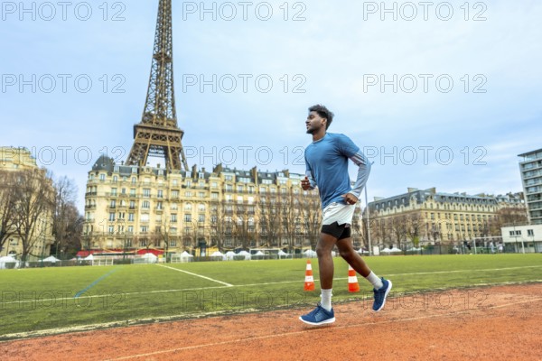 Male athlete running on a sports track in paris, focusing on fitness and active lifestyle in an urban setting with the iconic eiffel tower in the background under a cloudy sky