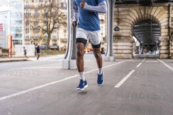 African american male athlete running on a dedicated paved track under the iconic bir hakeim bridge in paris, focusing on urban fitness and a healthy lifestyle