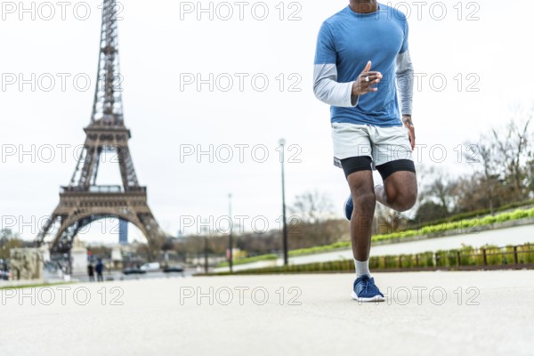 Athletic man jogging outdoors during his daily fitness workout routine, enjoying an active healthy lifestyle in the iconic city of paris with the eiffel tower in the background