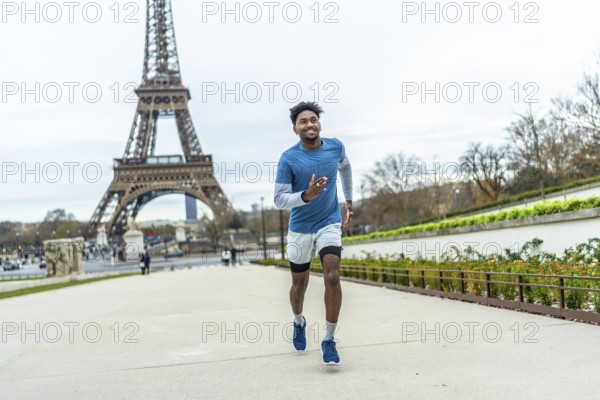 Young athletic black man jogging along paris streets, training outdoors near the eiffel tower, smiling and focused on fitness, endurance and healthy urban lifestyle