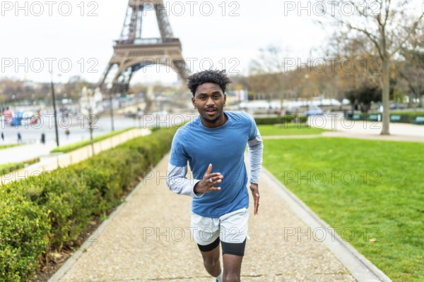 Young black man jogging along a path in a park, maintaining an active lifestyle and fitness routine with the iconic eiffel tower in the background, symbolizing urban health and well being