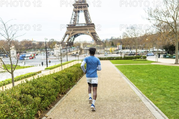 Young man exercising by running on a path in trocadero gardens, enjoying fitness and healthy lifestyle with the iconic eiffel tower dominating the paris skyline