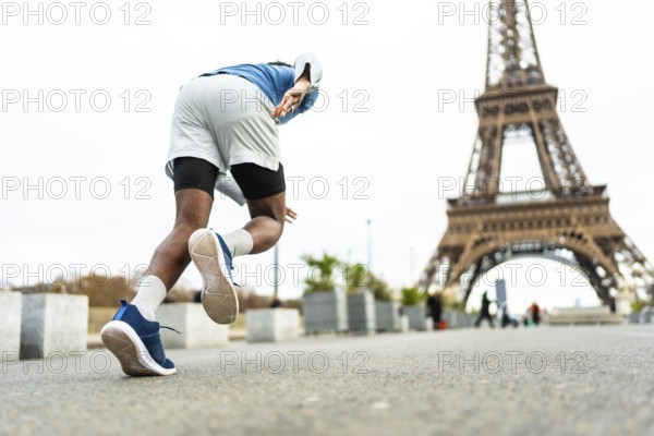 Male athlete starting to run in paris, training near the eiffel tower, symbolizing endurance, wellness, and an active lifestyle in a famous urban setting