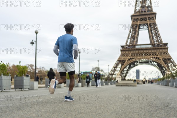 Man jogging for fitness and exercise on an urban street in paris with the iconic eiffel tower in the background, representing healthy lifestyle, travel, and sport in the city