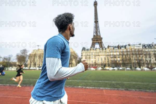 Young man training on a running track with the iconic eiffel tower and parisian buildings in the background, representing sport, fitness, and active lifestyle in the city