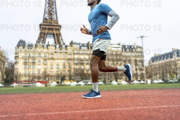 Male athlete with athletic sportswear running on an outdoor track in paris, focusing on fitness, urban sport, healthy lifestyle, and cardio exercise with the eiffel tower in the background