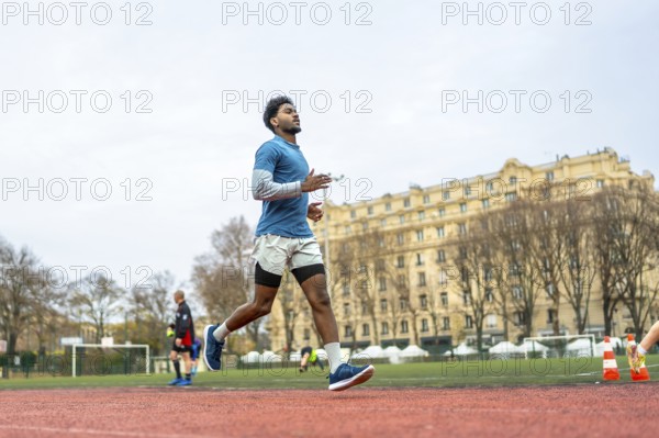 Young man training on a paris stadium running track, jogging in sportswear with focused determination, showcasing urban fitness, endurance and active healthy lifestyle outdoors