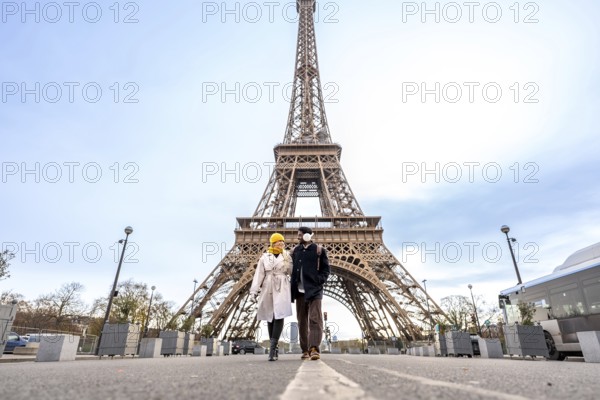 Young happy couple walking hand in hand during their city trip through paris, exploring the iconic eiffel tower and experiencing romance and international travel together