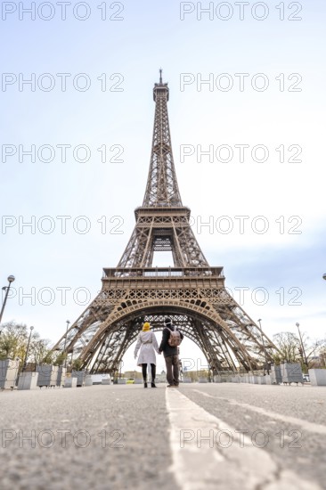 Couple holding hands walking down a street with a white line towards the eiffel tower on a bright day in paris, france, representing travel, romance, and shared experiences in a famous european city