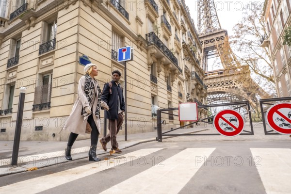 Diverse couple walking down a city street in paris, france, enjoying travel and leisure time together, with the famous eiffel tower towering in the background