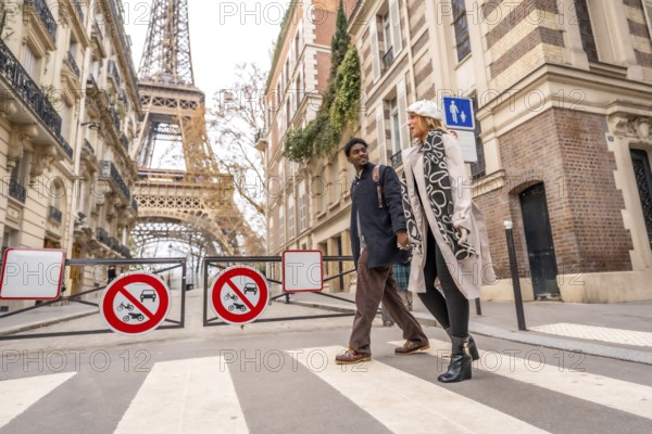Loving couple enjoying a romantic leisure walk in a charming parisian neighborhood, crossing a pedestrian street near classic architecture and views of the prominent eiffel tower