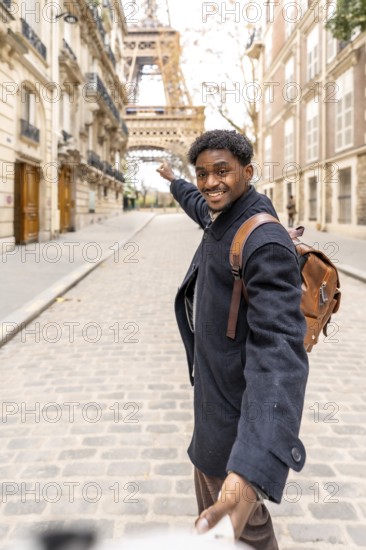 Happy black man leading someone by the hand down a cobblestone paris street, smiling and pointing toward the eiffel tower while enjoying a carefree travel moment