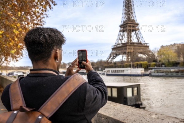 Traveler capturing a moment on smartphone while visiting the iconic eiffel tower in paris, engaging with city landmarks and culture during a european autumn trip