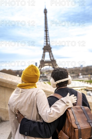 Loving couple standing with arms around each other, enjoying the view of the iconic eiffel tower in paris, celebrating their romantic travel adventure in the city of love