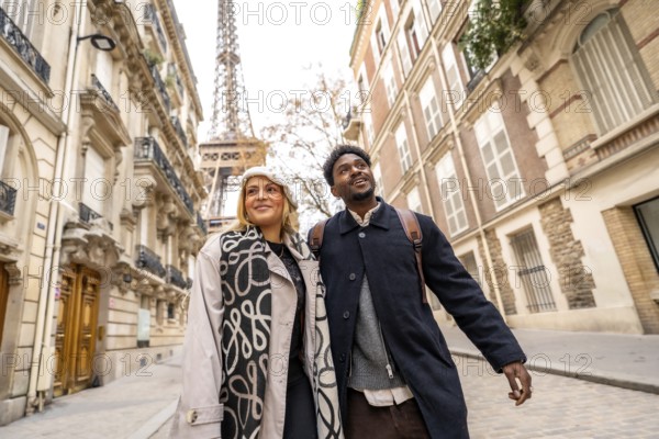 Diverse couple exploring a street in paris, france, looking up at the eiffel tower, experiencing romance and cultural tourism during their european vacation