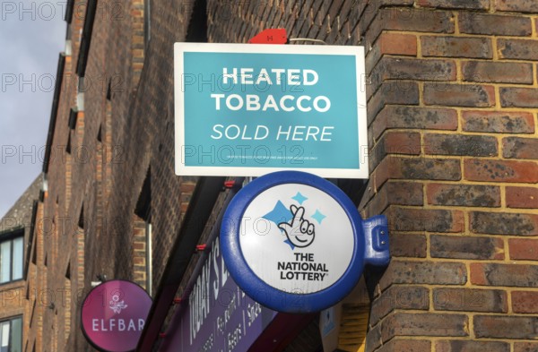 Wall mounted sign for Heated Tobacco Sold Here and The National Lottery, Reading, Berkshire, England, UK