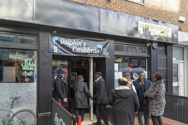 People outside Dolphin's Caribbean restaurant bar in town centre of Reading, Berkshire, England, UK