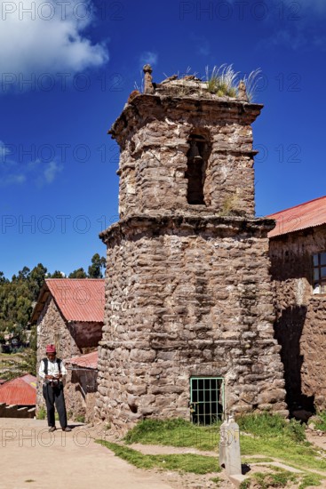 Old church tower with stone tower and a man in traditional clothing, The knitting men on the island of Taquile in Lake Titicaca in Peru