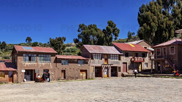 Traditional houses in a quiet village in the Andes, surrounded by nature and under a clear sky, The large town square on the island of Taquile in Lake Titicaca in Peru